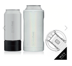 BrüMate insulated drinkware including a matte white Hopsulator Slim on a black base, a glitter white iridescent Toddy 22oz, and a clear MÜV Collection spill-proof lid with a white flip-top, all arranged on a white background