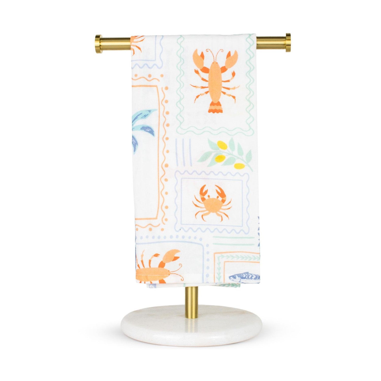 White cotton kitchen towel on a brass and white marble stand featuring a coastal pattern of orange lobsters, orange crabs, blue palm trees, and olive branches with yellow olives in postage stamp-like frames