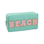 Teal textile cosmetic pouch featuring the word BEACH in pink chenille letters outlined in gold glitter with a gold zipper