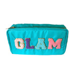A turquoise cosmetic pouch featuring the word GLAM in fuzzy colorful patch letters with gold outlines and a gold zipper