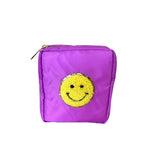A purple square cosmetic pouch featuring a textured yellow smiley face patch with a glittery gold outline and a matching gold zipper pull