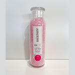 A clear glass bottle of Mixture brand Soothing Salt Soak filled with shimmering pink bath salts, featuring a distinctive white label with the bold pink No 22 detail on a minimalist white background