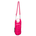 Photograph of a vibrant fuchsia pink quilted bottle holder bag with an adjustable striped shoulder strap and a small front zipper pocket presented against a white studio background