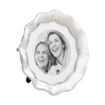 Silver scalloped round photo frame displaying a black and white photograph of two laughing women