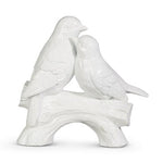 White ceramic sculpture of two lovebirds perched affectionately on a curved branch, featuring detailed feathers and a glossy finish