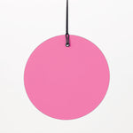 Photograph of a vibrant pink circular disc suspended by a black cord and small black metal loop against a plain white background