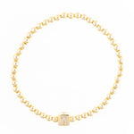 Gold beaded bracelet with a square charm featuring the letter T in crystals