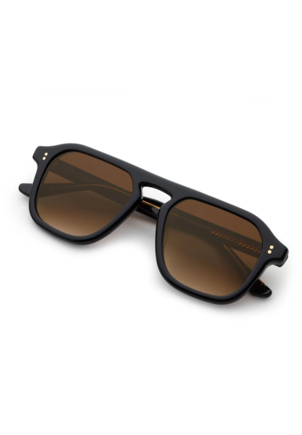 A pair of stylish black square frame sunglasses with brown gradient lenses and gold rivets on a white background