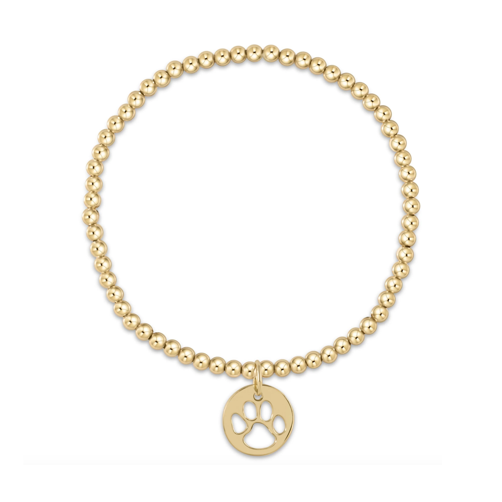 Gold beaded stretch bracelet with a circular charm featuring a cutout paw print