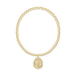 Gold beaded stretch bracelet with a round charm featuring an embossed American flag