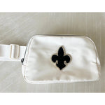 A white belt bag with a black fleur-de-lis emblem, gold accents, and a zipper closure.