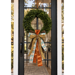 Black front door with a boxwood wreath finished with a copper, gold and aqua pumpkin-print ribbon bow