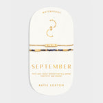 Two gold chain and lapis lazuli bead bracelets on a September birthstone display card