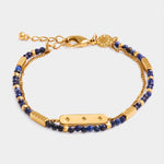 Gold chain bracelet with blue lapis lazuli beads and a central bar charm with star engravings