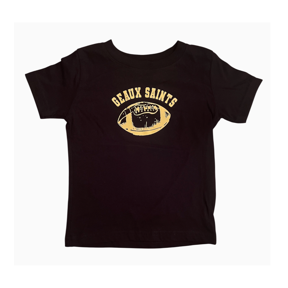 Screen-printed black cotton toddler t-shirt featuring a metallic gold Geaux Saints arched logo and a distressed football graphic centered on a white background