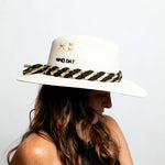 A person wearing a white hat with 'Who Dat' text and a black and yellow striped pattern on the brim.