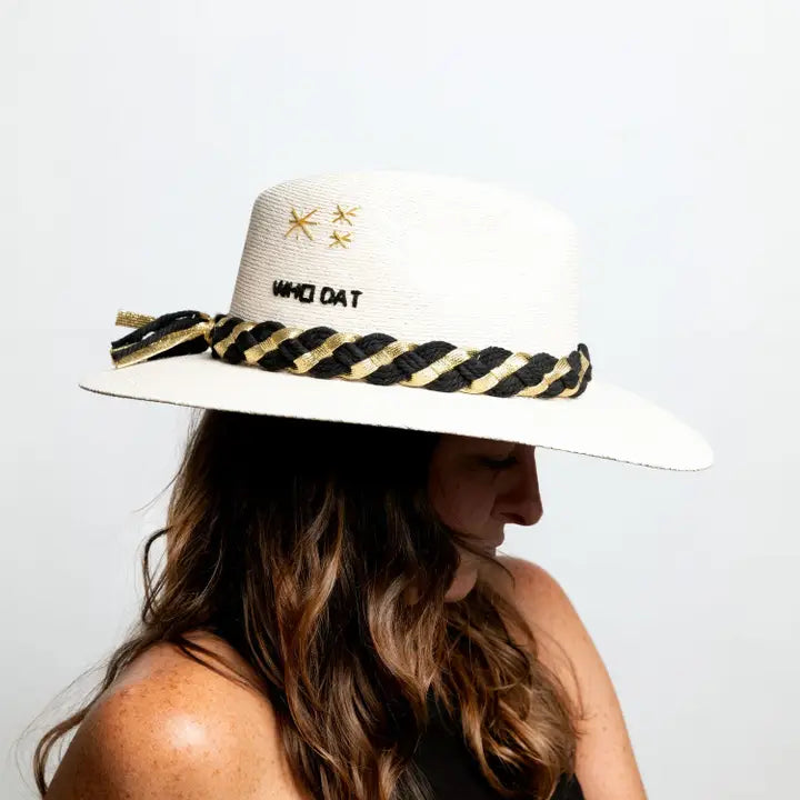 A person wearing a white hat with 'Who Dat' text and a black and yellow striped pattern on the brim.