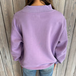 Person wearing a purple sweater against a wooden background