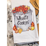 Kitchen towel with crawfish and corn design and 'What's Cookin'' text on a marble countertop.