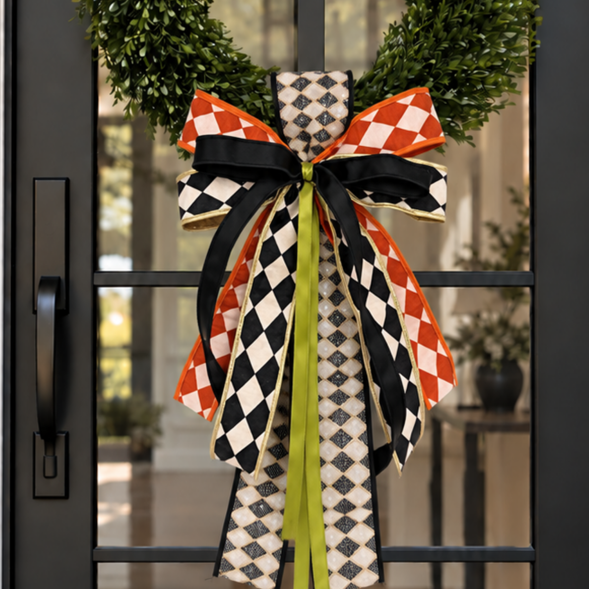 Candy corn striped sash and harlequin bow on a wreath on a black door
