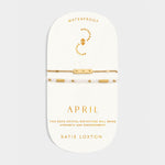 Two gold tone bracelets on a display card labeled April with rock crystal birthstone details