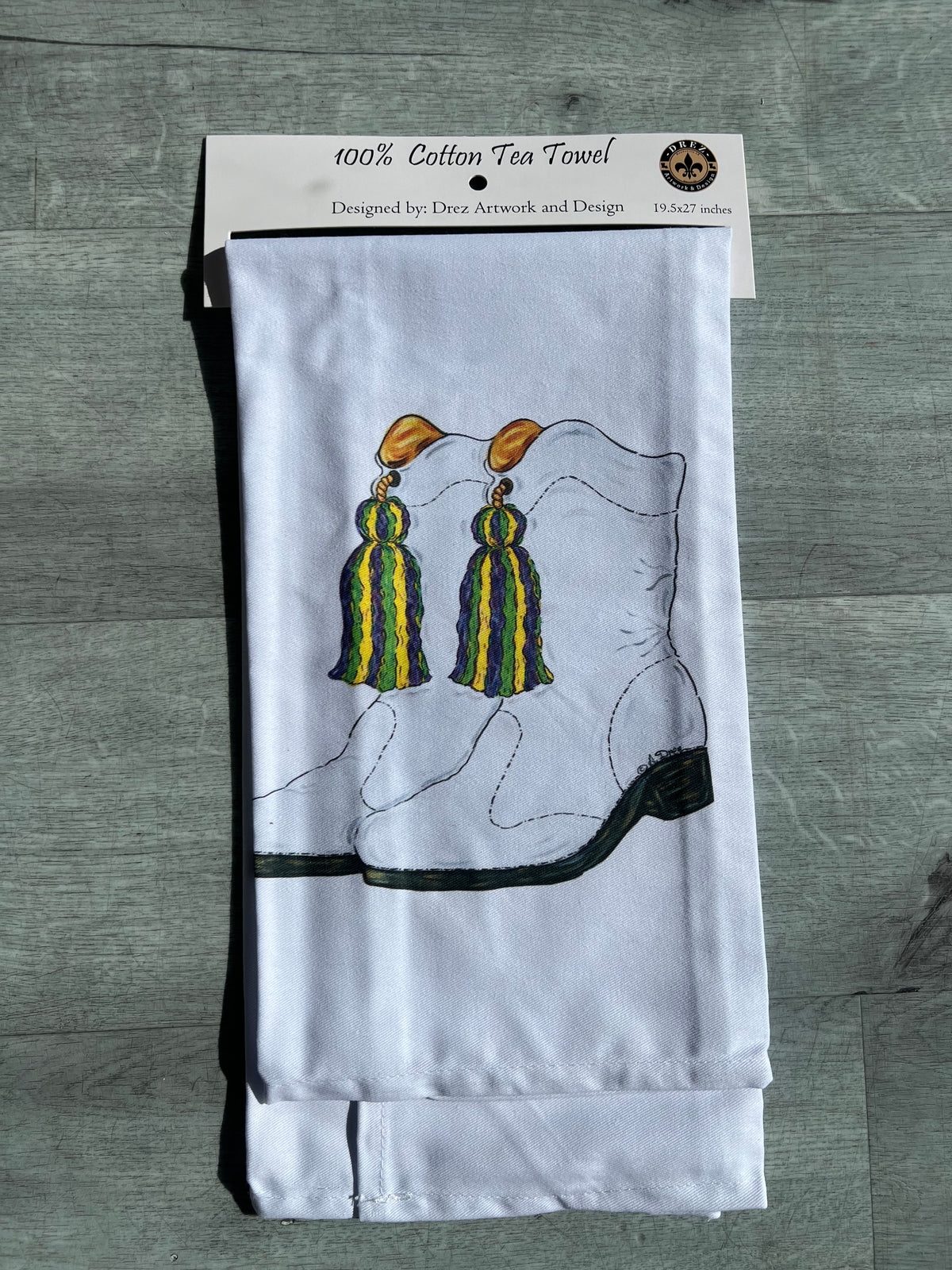 White tea towel with gold and green tassels in its package