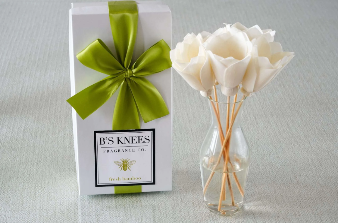 Bs Knees Fragrance Co gift box with green ribbon next to a glass vase with white flower reed diffusers