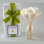 B'S Knees fragrance box with a green bow and white flowers in a vase on a light background