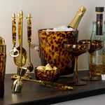 Tortoiseshell pattern barware set including ice bucket, cocktail glasses, jigger, and bar tools on a counter