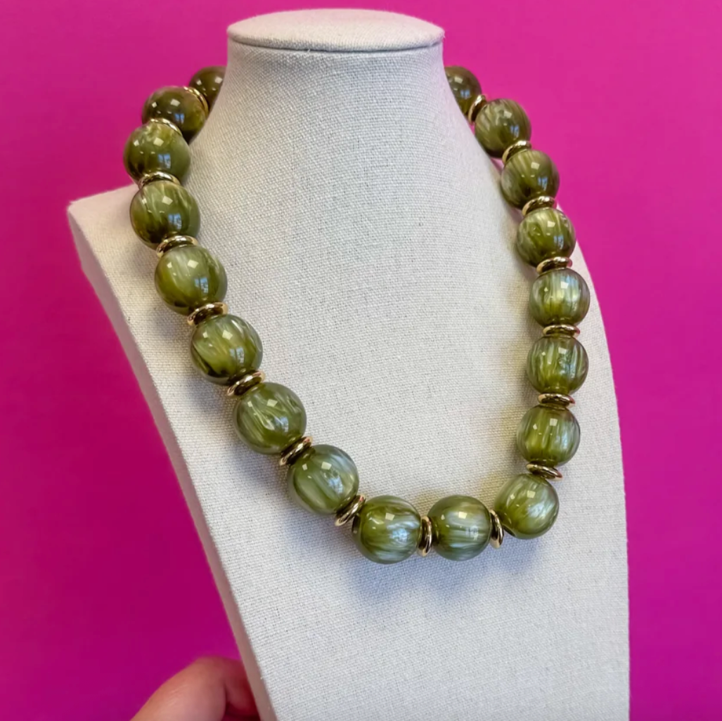 Green statement ball bead necklace with gold caps on a display bust