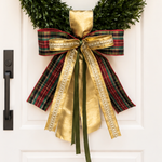 Bow of red and green tartan, gold satin, gold trim and dark green ribbons on a boxwood wreath