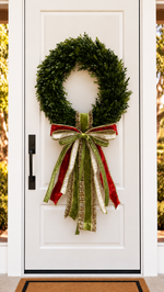 White front door with a boxwood wreath and a red, olive green and ivory ribbon bow