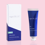 A small blue tube of Capri Blue Volcano Mini Hand Cream next to its white packaging box, both with the product name and ingredients listed.