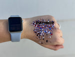A close-up photograph of a hand adorned with patriotic red, white, and blue glitter, featuring black text PATRIOT, and a light blue smartwatch on the wrist