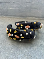 A black headband with a football design, featuring gold-colored beads and pearls.