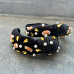 A black headband with a football design, featuring gold-colored beads and pearls.