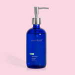 A cobalt blue glass bottle with a pump dispenser, labeled 'capri BLUE volcano', on a pink background.