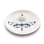 White ceramic incense holder featuring a stylized blue and white dragonfly with translucent wing patterns a dotted tail and a central spherical stick holder