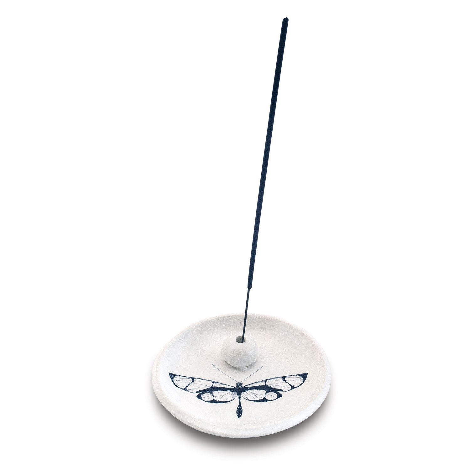 White ceramic circular incense holder decorated with a black stylized dragonfly motif holding an upright black incense stick