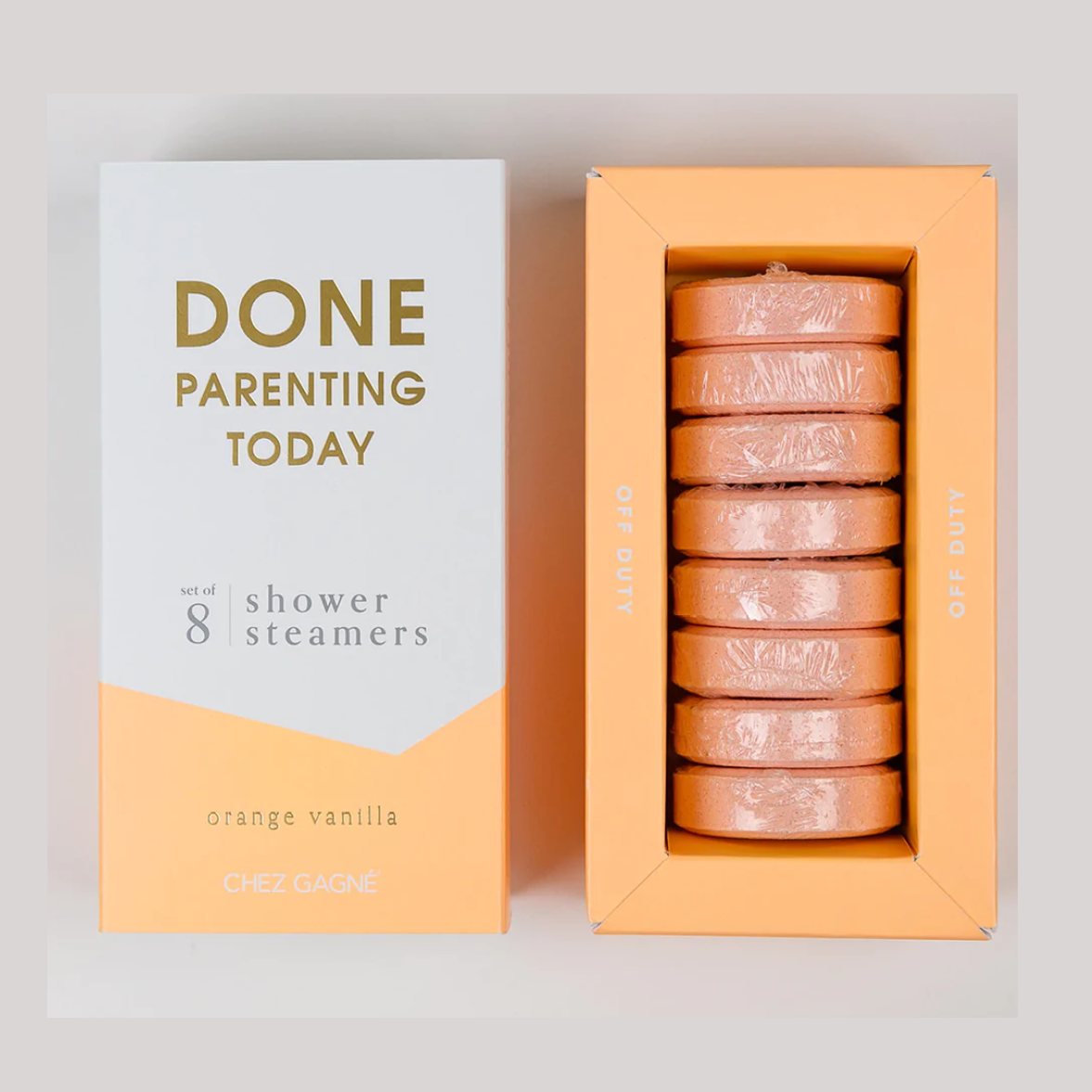Chez Gagné orange vanilla shower steamers, a white and orange box with "DONE PARENTING TODAY" in gold text stands next to an open orange box displaying eight individually wrapped coral tablets stacked vertically with "OFF DUTY" written on the sides