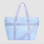 CORKCICLE insulated tote bag in light blue featuring prominent lavender purple straps with repeating embossed CORKCICLE text and a small dark blue brand logo on the front panel