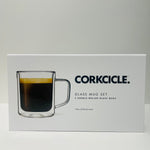 Digital photograph by Corkcicle of a white product box for their Glass Mug Set showcasing a clear double-walled glass mug filled with dark coffee and golden crema, branded with the black CORKCICLE logo and product text '2 DOUBLE-WALLED GLASS MUGS' and '12oz (355ml) each' on a simple white studio background