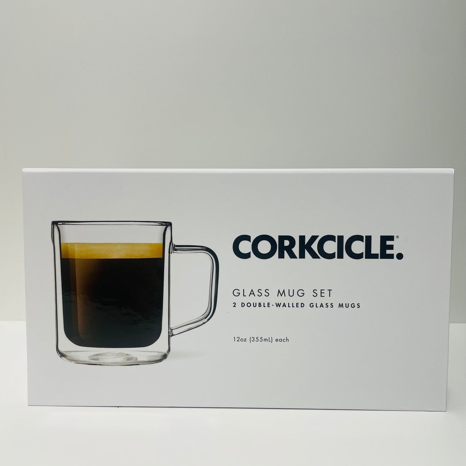 Digital photograph by Corkcicle of a white product box for their Glass Mug Set showcasing a clear double-walled glass mug filled with dark coffee and golden crema, branded with the black CORKCICLE logo and product text '2 DOUBLE-WALLED GLASS MUGS' and '12oz (355ml) each' on a simple white studio background