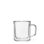 Product photography of a sleek double-walled clear glass mug featuring a distinctive rectangular handle against a solid green background