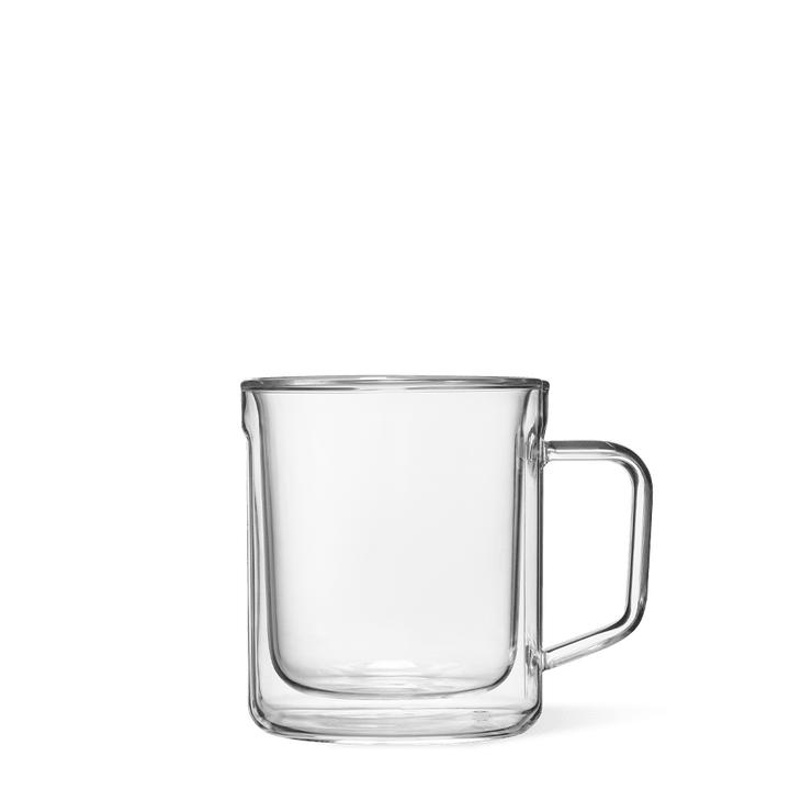 Product photography of a sleek double-walled clear glass mug featuring a distinctive rectangular handle against a solid green background