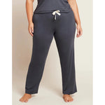 A person standing wearing grey 
sleep pants with a drawstring and a wide leg design.