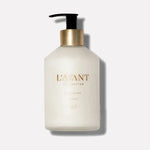 Product photo of a L'AVANT COLLECTIVE Hand Lotion white pump bottle with a black dispenser and gold neck band on a clean studio background featuring elegant gold text