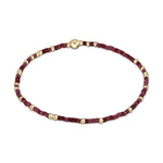 Beaded bracelet featuring a pattern of gold spherical beads and deep red and maroon cube-shaped beads with a central gold clasp