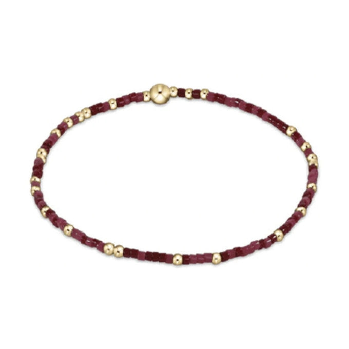 Beaded bracelet featuring a pattern of gold spherical beads and deep red and maroon cube-shaped beads with a central gold clasp