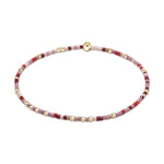 Delicate beaded bracelet crafted from small seed beads in shades of red, pink, and burgundy, interspersed with small golden spherical beads and secured by a prominent golden button clasp